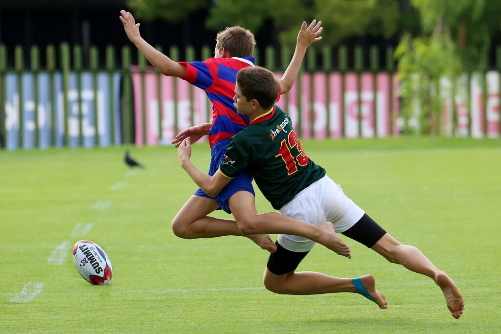 Energetic teenage boys playing rugby on a sunny day, showcasing teamwork and competition.